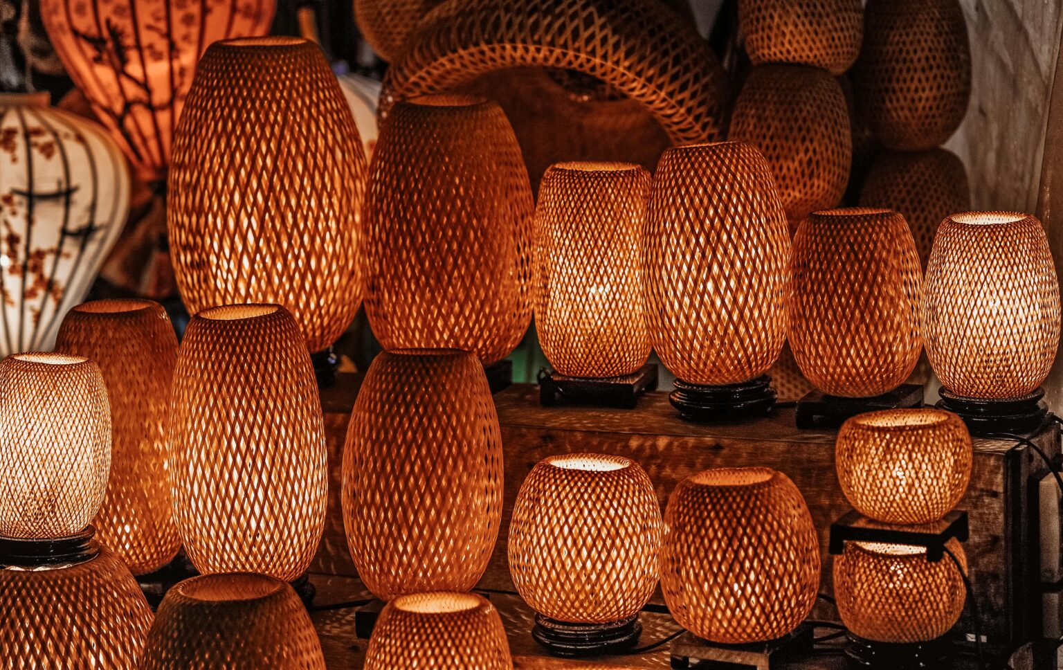 A collection of handmade woven lamps with warm glow indoors, showcasing traditional craftsmanship.